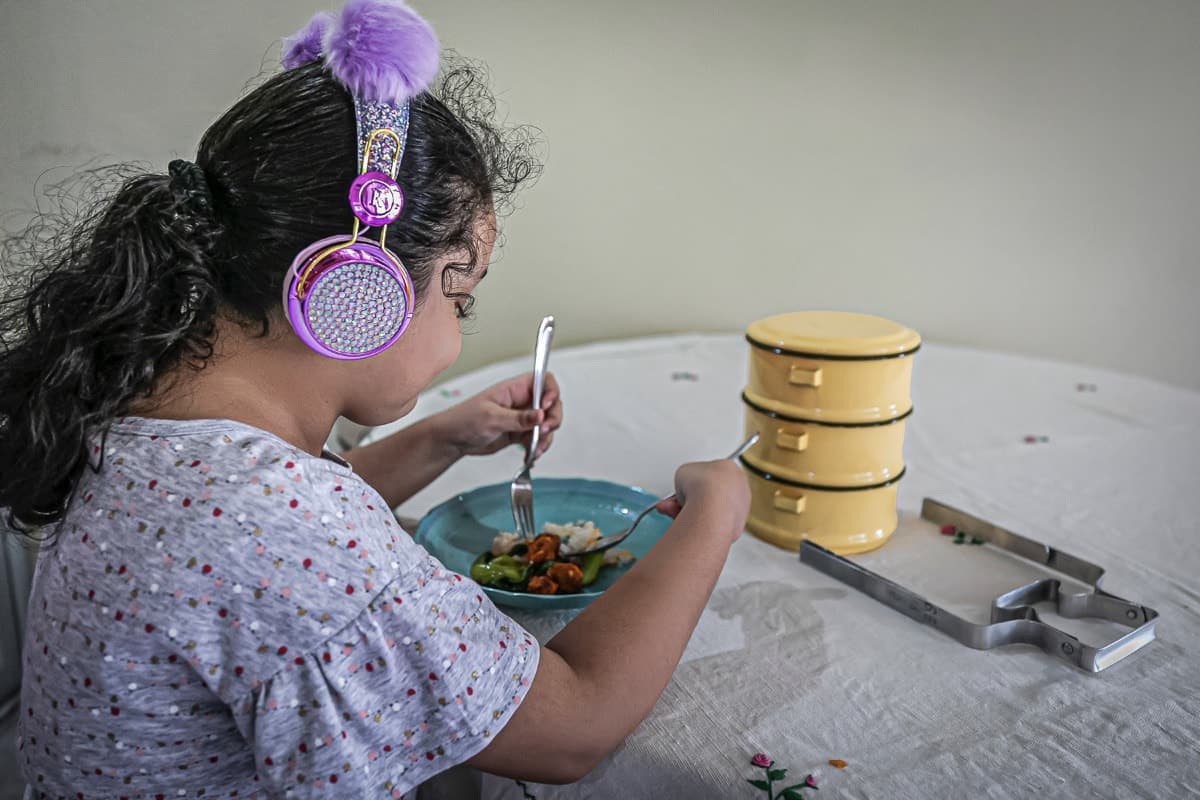 A child participant of The Little Cooking Club That Could tucks into her meal while listening to the artist's audio guide. Image courtesy of TLOCCTC.