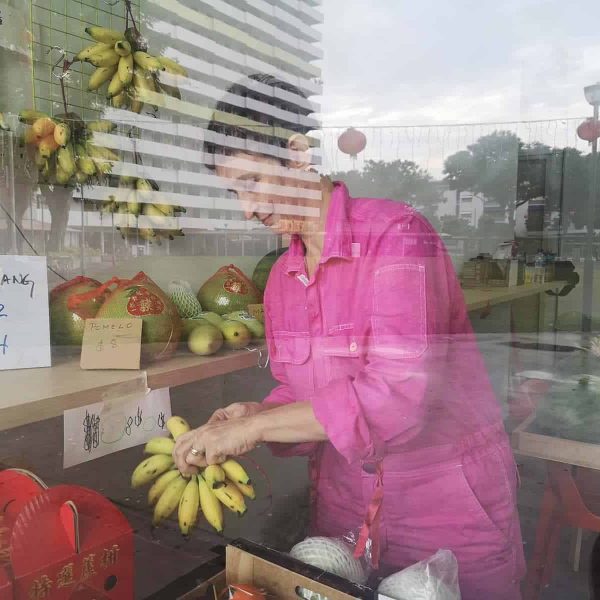 The artist, her kopi, and her studio-in-a-fruit-stall, King of Fruits, in the background.